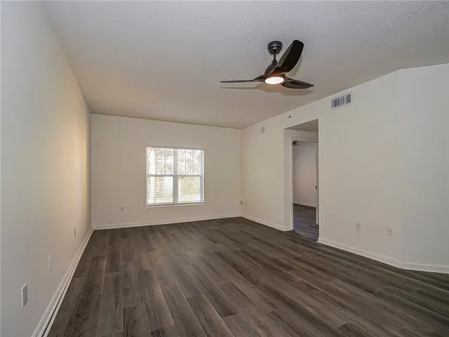 a view of empty room with wooden floor and window