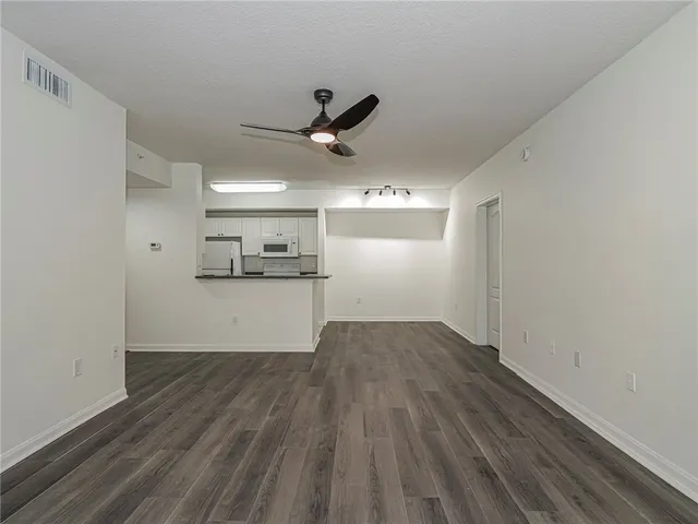 a view of kitchen and empty room with wooden floor