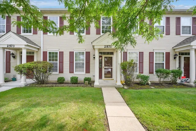 a front view of a house with a yard and potted plants