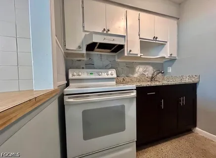 a kitchen with stainless steel appliances granite countertop white cabinets and a stove