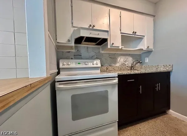 a kitchen with stainless steel appliances granite countertop white cabinets and a stove