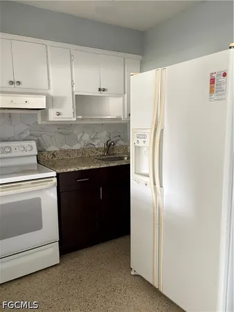 a kitchen with stainless steel appliances granite countertop a refrigerator sink and white cabinets