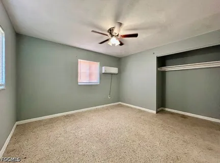 an empty room with windows and fan
