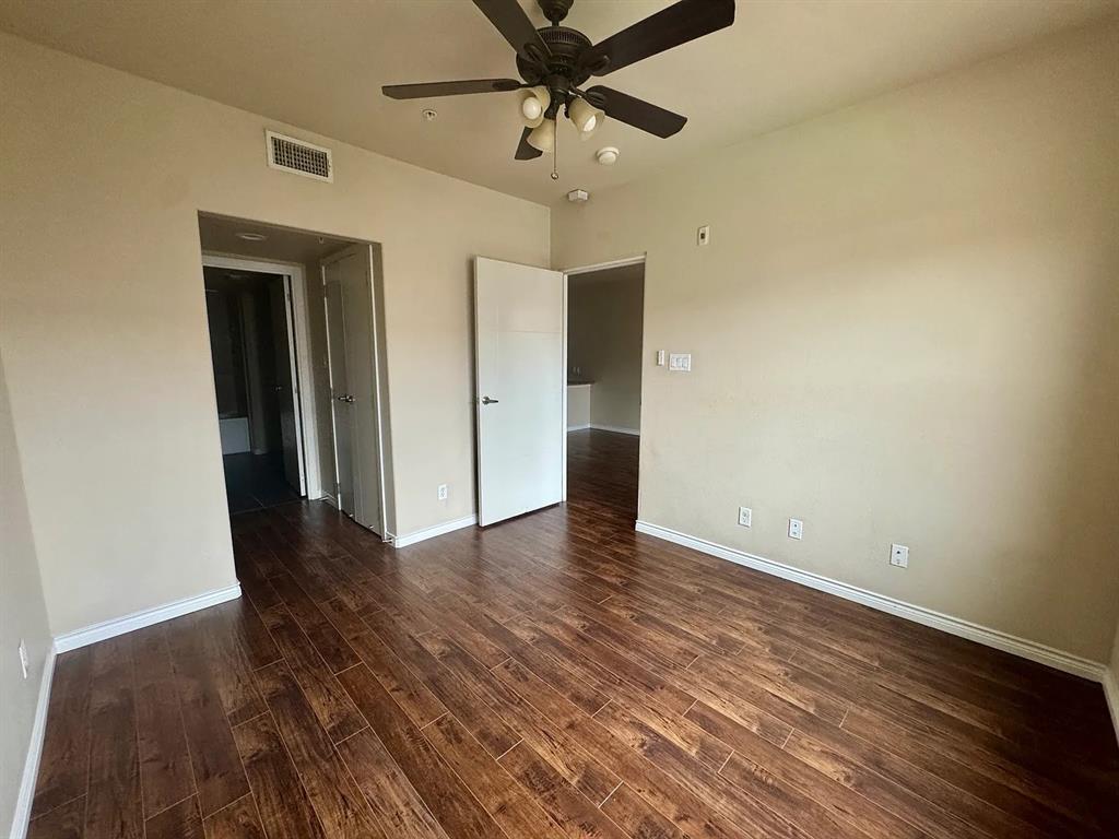 1100 West Trinity Mills Road, Unit 3010 Carrollton, TX 75006 - Photo 3 of 10 a view of an empty room with a ceiling fan wooden floor and a ceiling fan