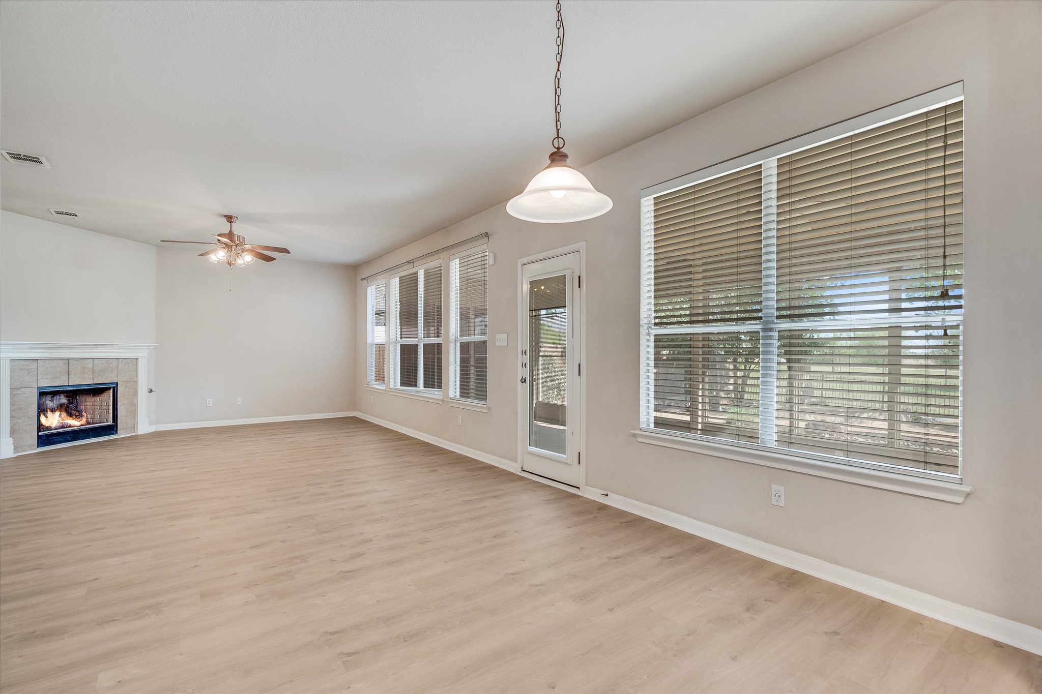 4029 Lake Edge Way Pflugerville, TX 78660 - Photo 10 of 35 Unfurnished living room with a tile fireplace, light wood finished floors, and a ceiling fan