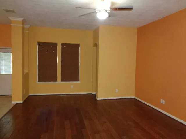 a view of an empty room with wooden floor and a window