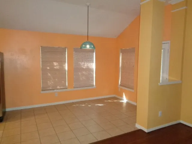 a view of an empty room with window and chandelier fan