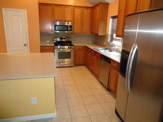 a kitchen with stainless steel appliances granite countertop a refrigerator a stove a sink and a microwave