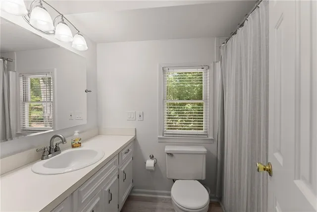 a bathroom with a granite countertop sink toilet a large mirror and a window