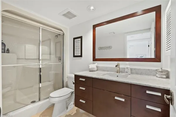 a bathroom with a toilet a sink a glass door a shower and a mirror