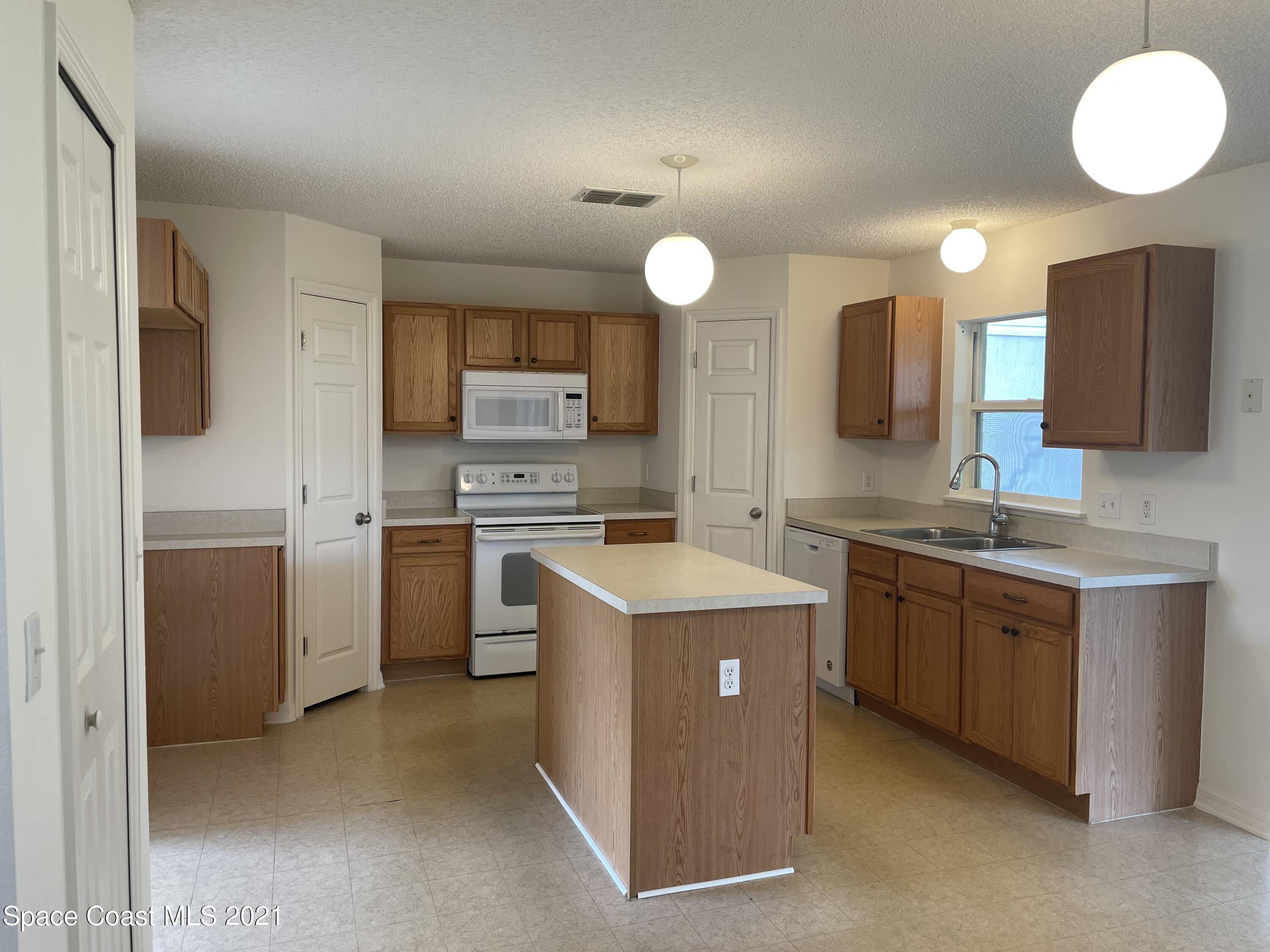 2315 Canopy Drive Melbourne, FL 32935 - Photo 5 of 27 a kitchen with a stove sink and a refrigerator