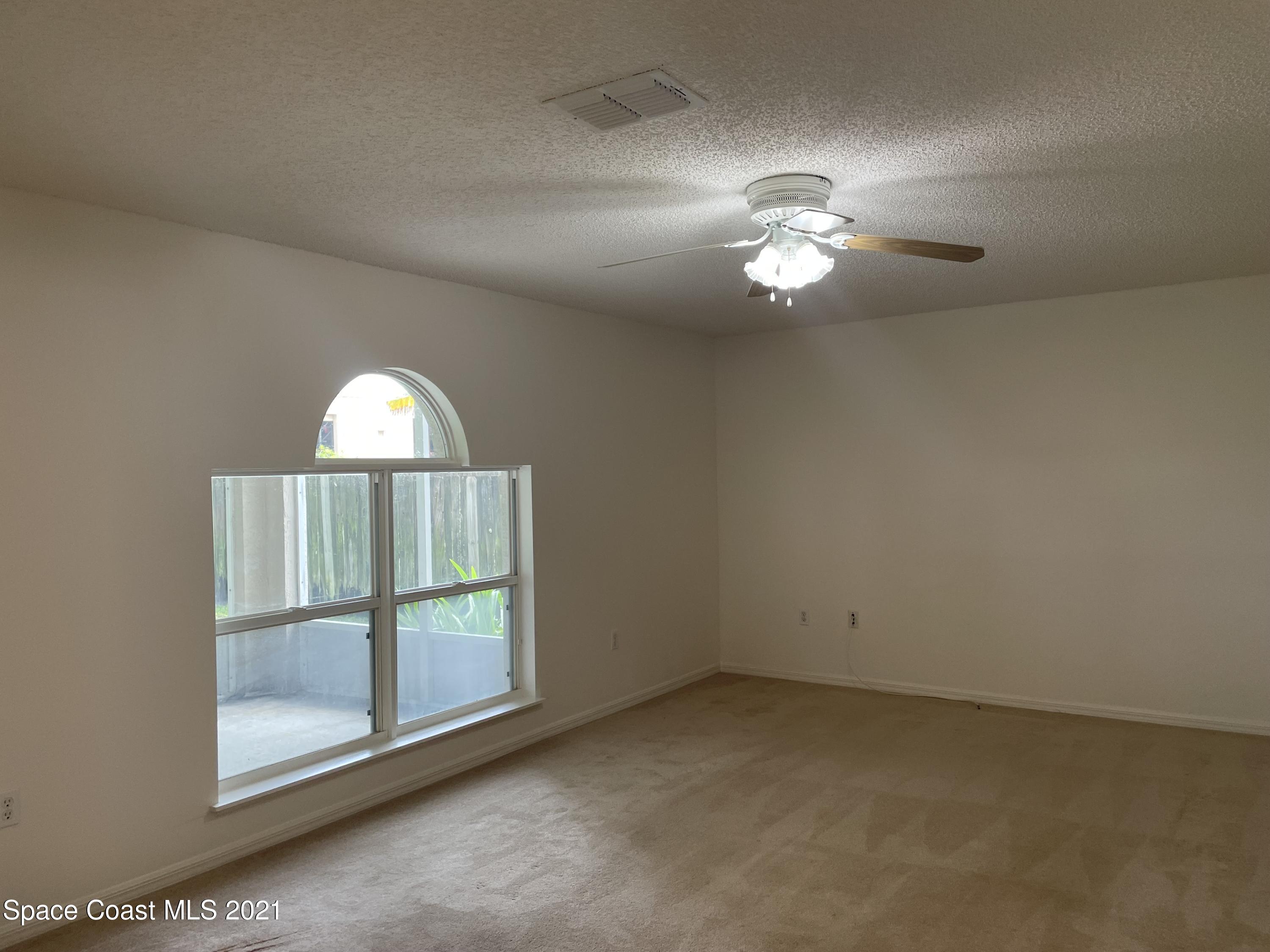 2315 Canopy Drive Melbourne, FL 32935 - Photo 7 of 27 an empty room with wooden floor fan and windows