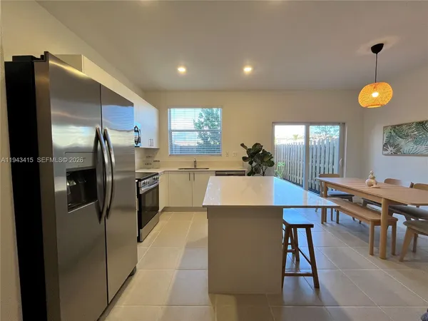 a kitchen with stainless steel appliances kitchen island granite countertop a refrigerator a stove a sink a dining table and chairs