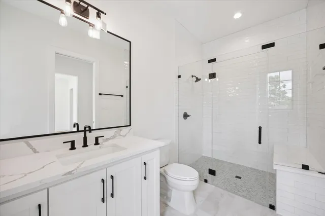 a bathroom with a sink a toilet a mirror and shower