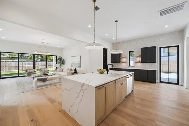 a large kitchen with kitchen island a large counter top stainless steel appliances and a large window
