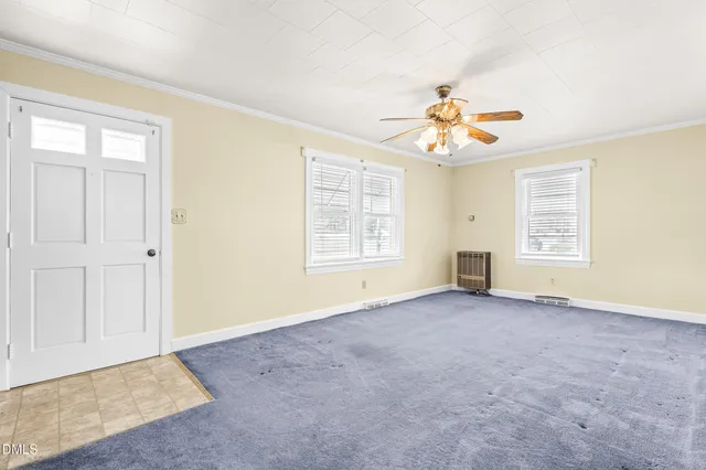 an empty room with windows and chandelier fan