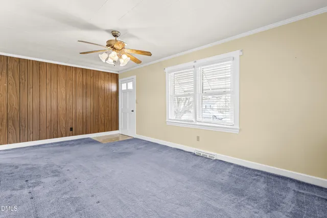 an empty room with windows and fan