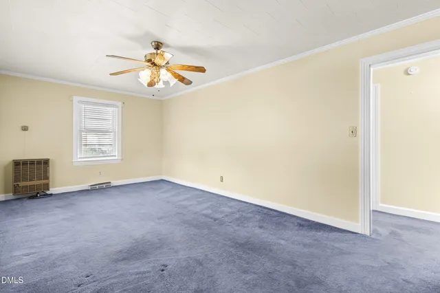 an empty room with windows and chandelier fan