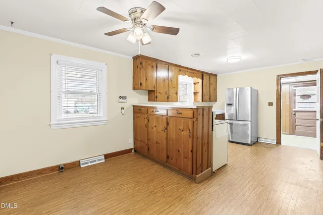 a view of a kitchen with a stove cabinets a ceiling fan and wooden floor