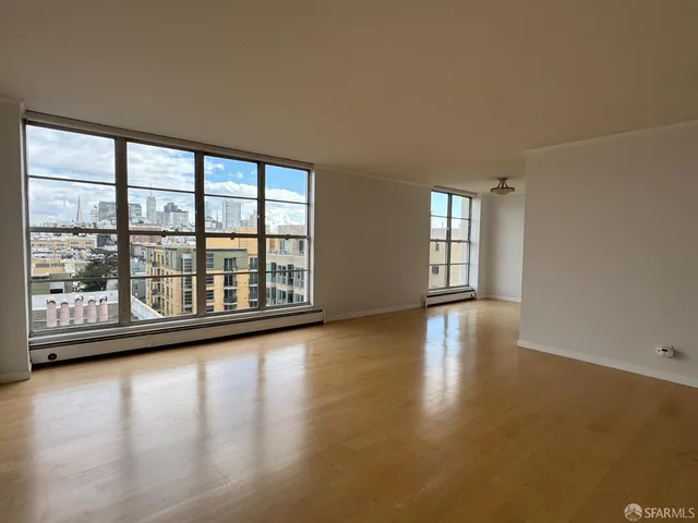 a view of empty room with wooden floor and fan