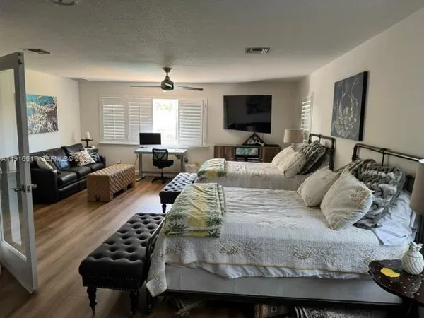 a bedroom with a bed a couch and a flat screen tv