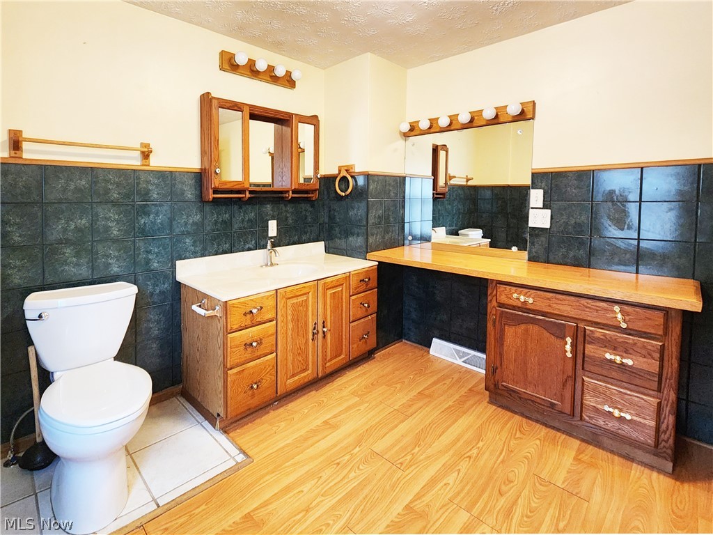 30 West Wilbeth Road, Unit A Akron, OH 44301 - Photo 11 of 16 Bathroom with vanity, wood-type flooring, tile walls, toilet, and a textured ceiling