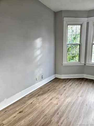 an empty room with wooden floor and window