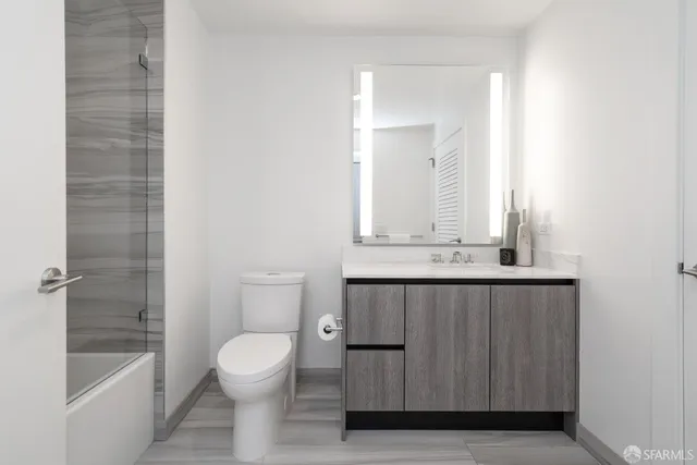 a bathroom with a granite countertop sink a toilet and bathtub