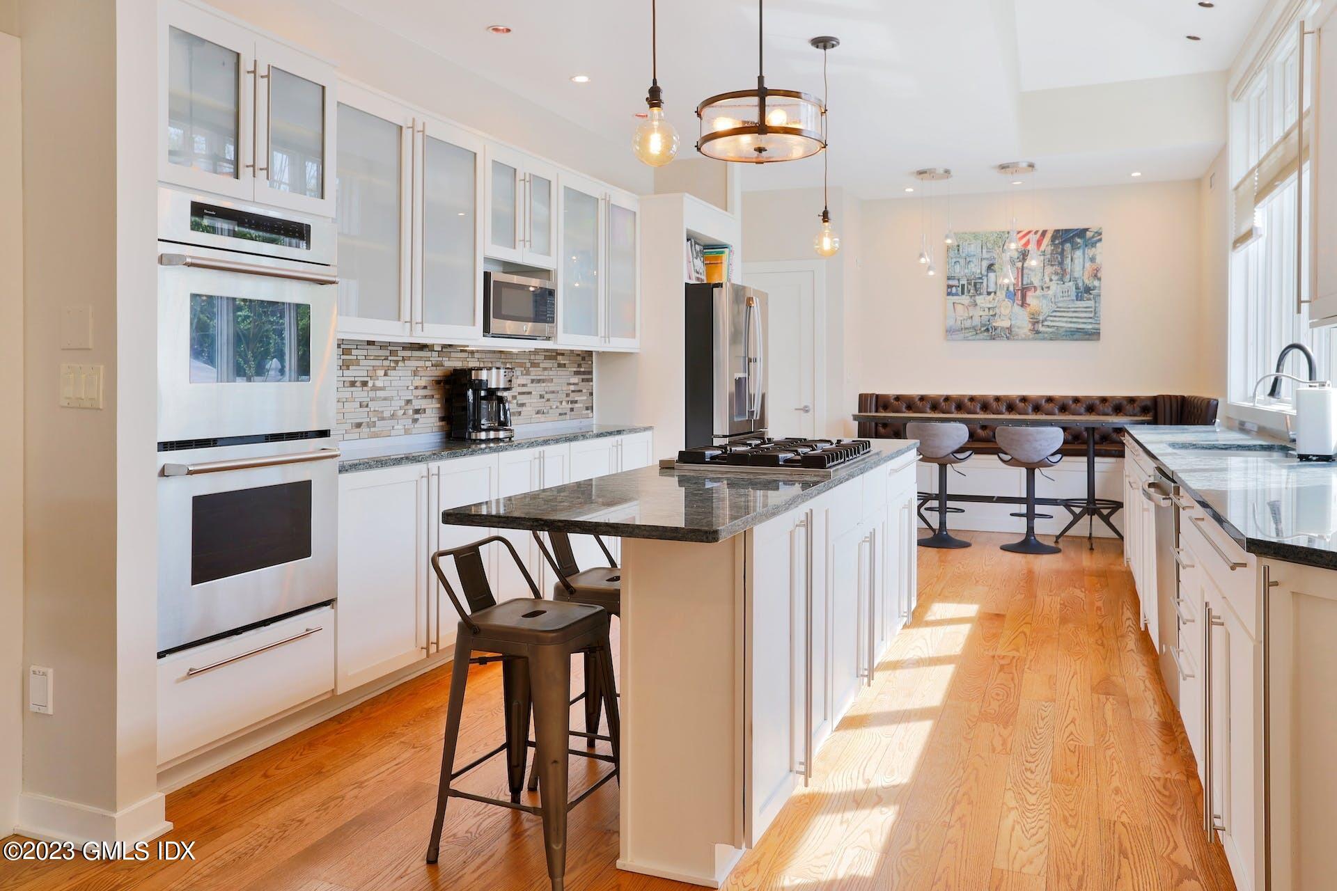 62 Morningside Drive Greenwich, CT 06830 - Photo 14 of 31 a kitchen with stainless steel appliances granite countertop a stove top oven a sink a dining table and chairs with white cabinets