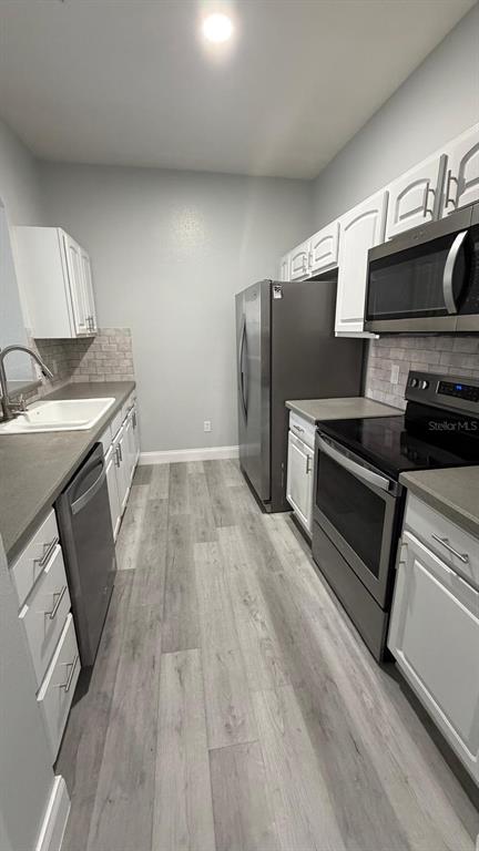 13584 Turtle Marsh Loop, Unit 113 Orlando, FL 32837 - Photo 19 of 29 a kitchen with wooden floors and stainless steel appliances