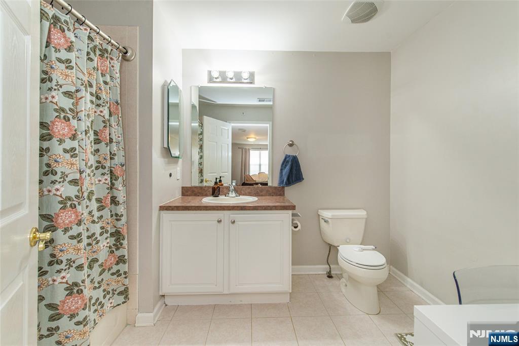454 Cambridge Drive Butler, NJ 07405 - Photo 11 of 38 a bathroom with a granite countertop sink a toilet and a mirror