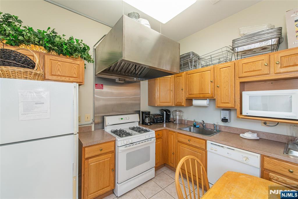 454 Cambridge Drive Butler, NJ 07405 - Photo 24 of 38 a kitchen with a refrigerator a stove a sink dishwasher and wooden cabinets with wooden floor