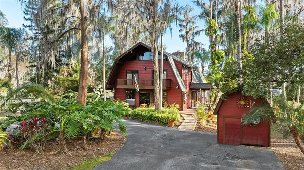 a view of a house with a yard and large trees