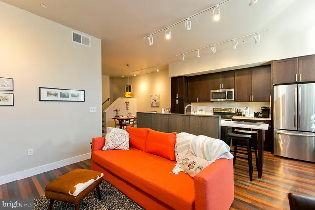 a kitchen with stainless steel appliances kitchen island granite countertop a refrigerator a stove a sink a dining table and chairs with wooden floor