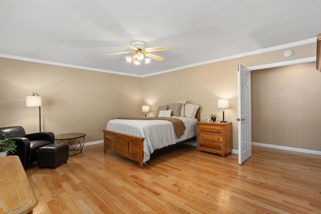 2614 Secret Lake Lane Fallbrook, CA 92028 - Photo 20 of 60 a spacious bedroom with a bed and a chandelier