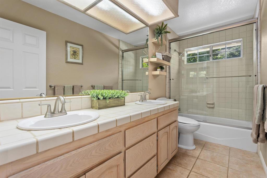 2614 Secret Lake Lane Fallbrook, CA 92028 - Photo 25 of 60 a bathroom with a granite countertop sink a toilet a mirror a bathtub and shower