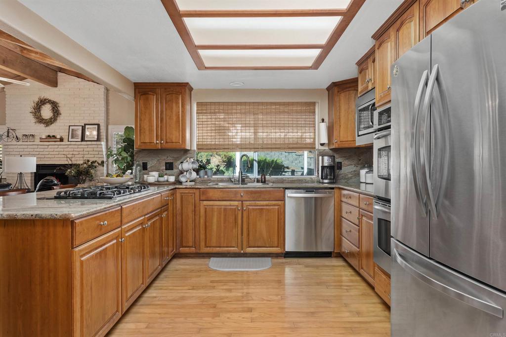 2614 Secret Lake Lane Fallbrook, CA 92028 - Photo 10 of 60 a kitchen with stainless steel appliances granite countertop a refrigerator a sink dishwasher a stove and white countertops with wooden floor