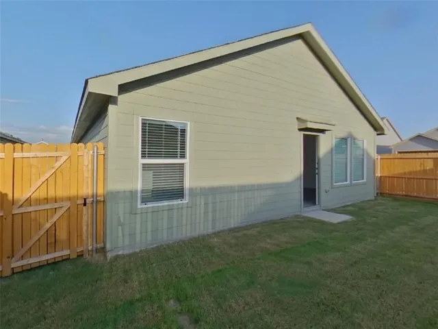 a backyard of a house with plants and wooden fence