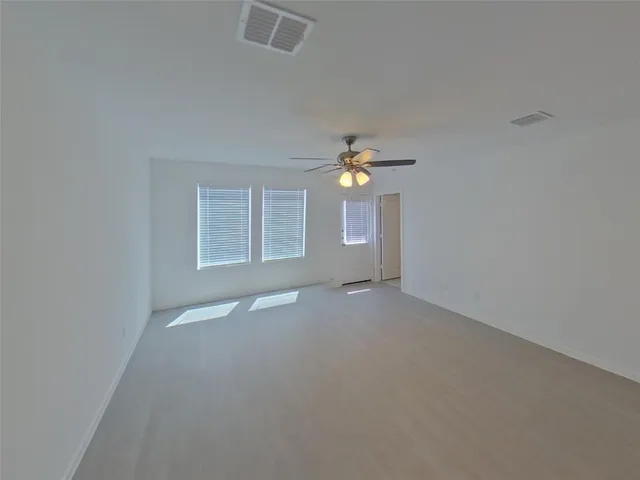 an empty room with windows and chandelier fan