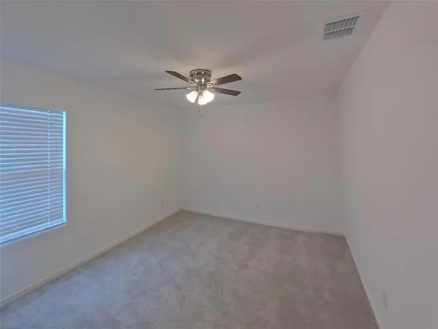an empty room with a window and a fan
