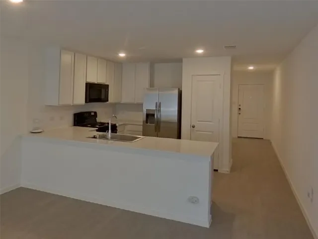 a view of kitchen with stainless steel appliances refrigerator stove microwave and cabinets