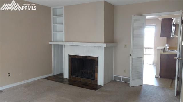 327 Raspberry Lane Monument, CO 80132 - Photo 2 of 16 Spacious Living Room with wood-burning fireplace and built-in bookshelves. Access the Kitchen and Dining Area through the doorway at right.