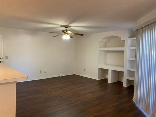 an empty room with wooden floor closet and windows