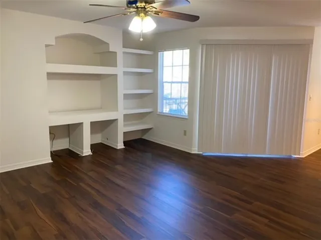 an empty room with wooden floor closet and windows