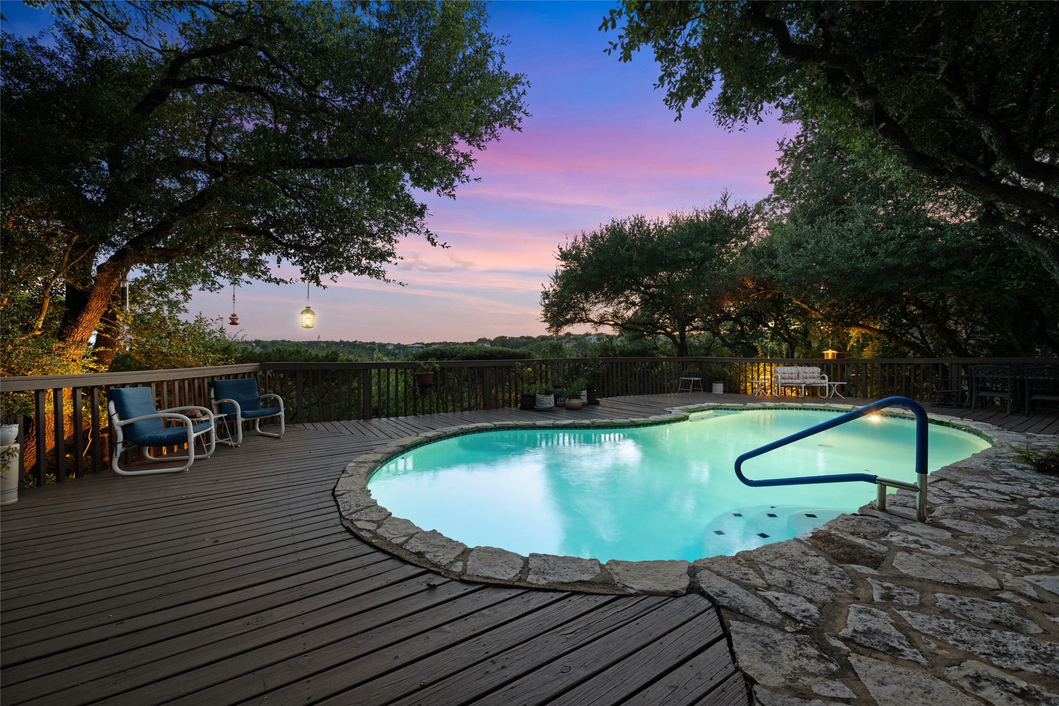 5319 Musket Ridge Austin, TX 78759 - Photo 34 of 39 An inviting pool and wood deck offer expansive views under a vibrant sunset sky.