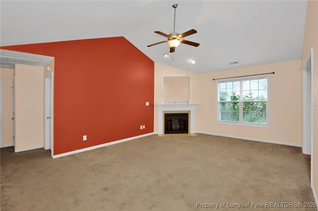an empty room with windows fireplace and fan