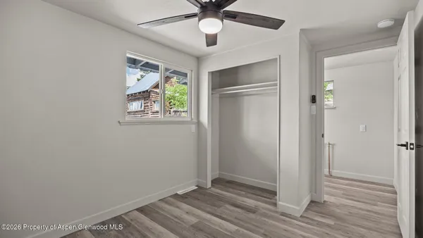 a view of an empty room with wooden floor and a window