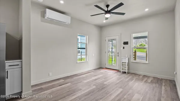 a view of an empty room with window and wooden floor