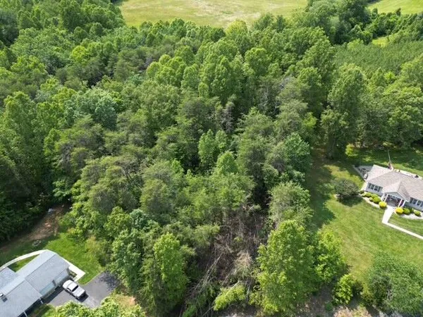 an aerial view of residential house with outdoor space and trees all around