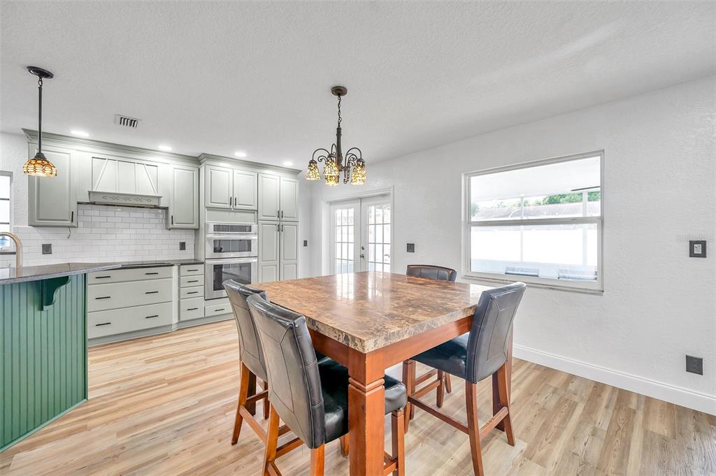 1520 Windmill Pointe Road Palm Harbor, FL 34685 - Photo 13 of 64 a kitchen with stainless steel appliances granite countertop a kitchen island hardwood floor sink stove dining table and chairs